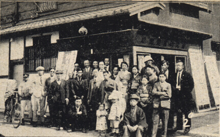 1927_osaka 1 (1) old sepia-toned photo of a group of people standing in front of a building