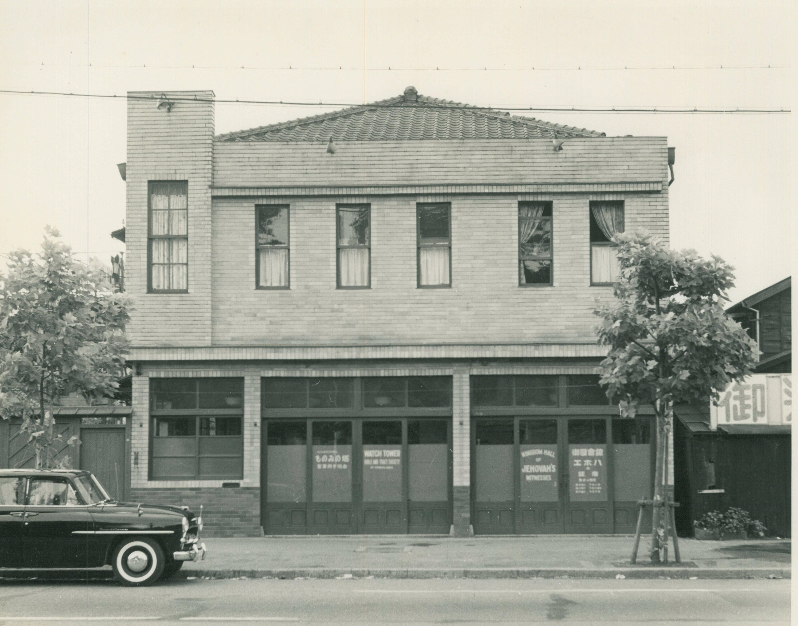 G-1196 _1 an old photo of a building with a car sitting out front