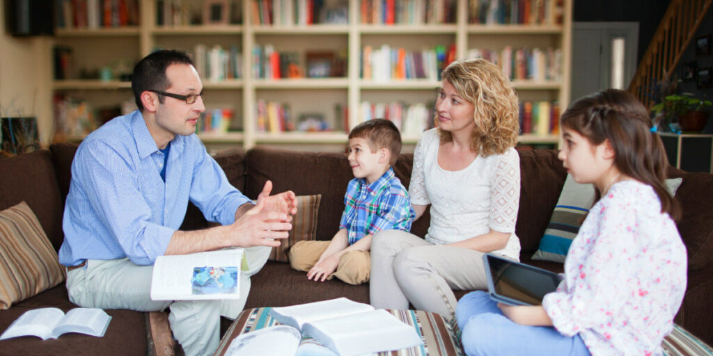 a man sitting with his family talking while his son, daughter, and wife are listening