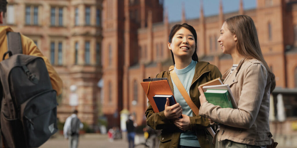 2 students conversing while walking across a university campus